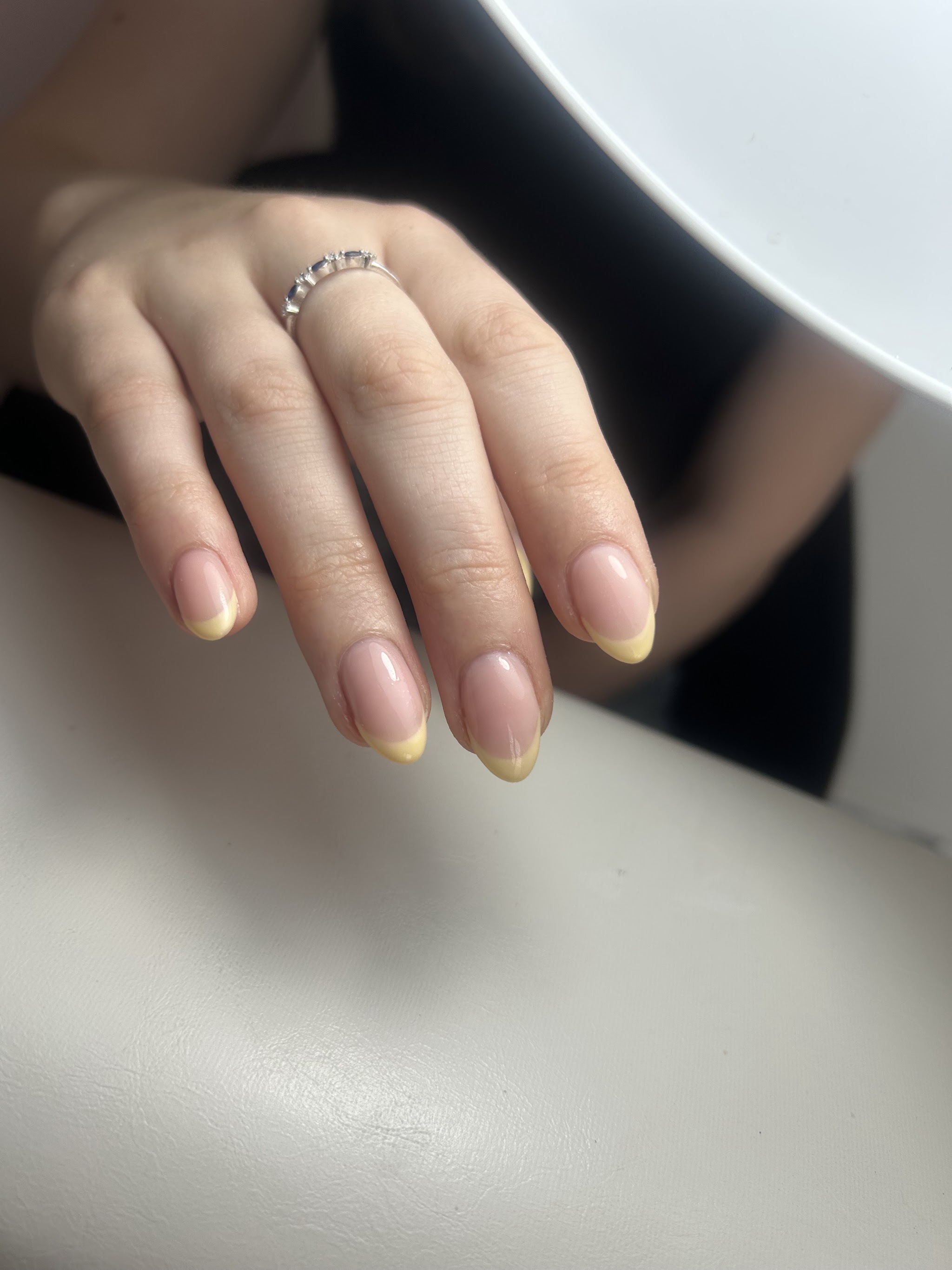 Naturel nagels met zachtgele French tips en een ring